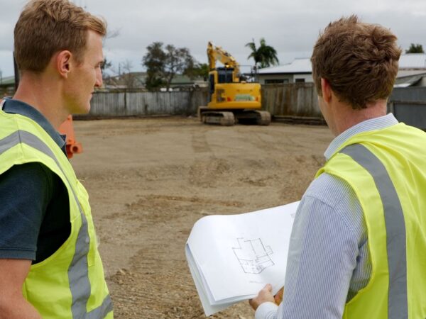 Image of two men looking over architectural plans at a building site